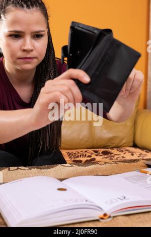 Un adolescente adulto tiene un portafoglio vuoto nelle sue mani. Cattiva gestione del bilancio delle famiglie quando si è molto sprecato durante e Foto Stock