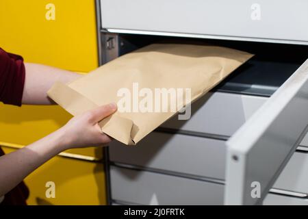 La ragazza ha aperto una scatola con il pacchetto che ha ordinato due giorni fa. Un elemento del telaio aperto. Lettera in busta grigia. Foto Stock