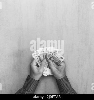 Carta cinque migliaia di banconote rubli russe nelle mani dell'uomo su sfondo grigio con spazio f Foto Stock