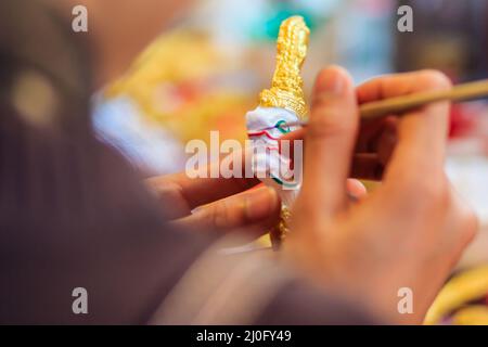 Vicino la mano di scultore tailandese durante la verniciatura del capolavoro di modelli di burattini, Foto Stock