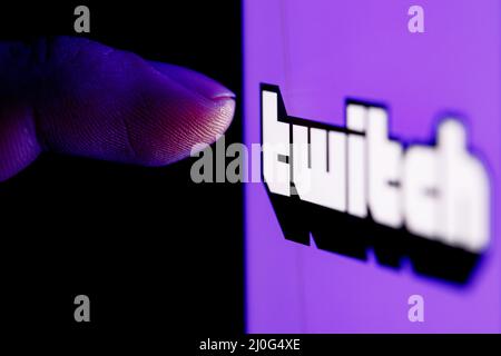 Il dito raggiunge il logo del servizio di streaming live Twitch sullo schermo dello smartphone. Foto Stock