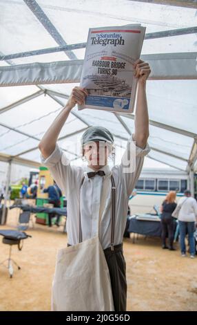 Sydney. 19th Mar 2022. Un venditore di giornali in costume mostra un giornale vicino al Ponte dell'Porto a Sydney, Australia, il 19 marzo 2022, come parte della celebrazione del 90th anniversario del Ponte dell'Porto di Sydney. Per celebrare il 90th anno dal completamento del Sydney Harbour Bridge, il sabato Sydneysiders si è recato nel porto per rendere omaggio al ponte che ha collegato e ispirato generazioni di australiani. Credit: Bai Xuefei/Xinhua/Alamy Live News Foto Stock