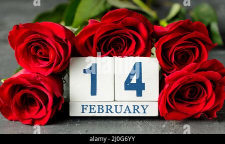 Concetto di giorno di San Valentino con rose rosse e calendario cubico. 14 di febbraio, giorno di festa Foto Stock