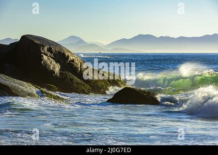 Onde che si infrangono contro le rocce all'alba d'estate sulla spiaggia del diavolo a Ipanema Foto Stock