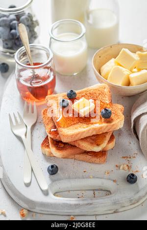Toast alla francese gustosi e freschi con frutti di bosco, sciroppo d'acero e burro. Toast alla francese dorata con burro e miele. Foto Stock