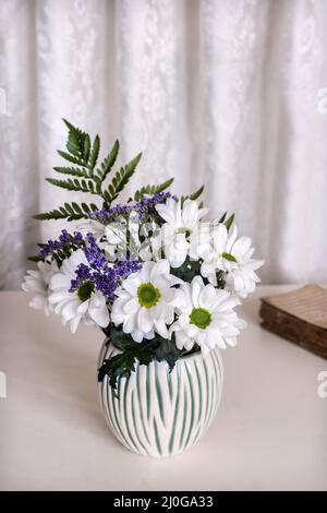 Crisantemi bianchi sul tavolo in vaso di ceramica Foto Stock