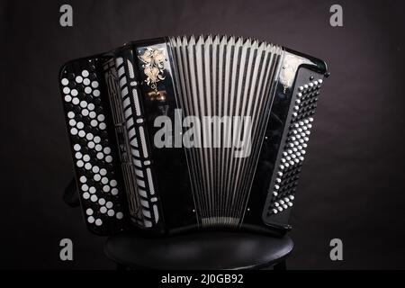 Strumenti musicali folk russi. La fisarmonica nera è isolata su uno sfondo scuro Foto Stock
