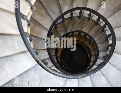 Vecchia scala a chiocciola con gradini in marmo e corrimano in ferro battuto Foto Stock