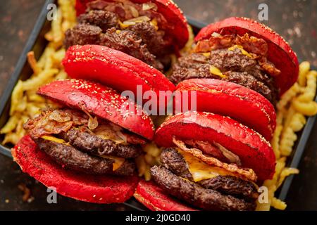 Set di quattro hamburger di formaggio becon doppio fatti in casa. Servita con patatine fritte su tavola di legno. Foto Stock