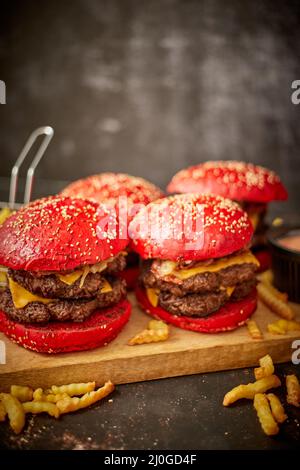 Set di quattro hamburger di formaggio becon doppio fatti in casa. Servita con patatine fritte su tavola di legno. Foto Stock