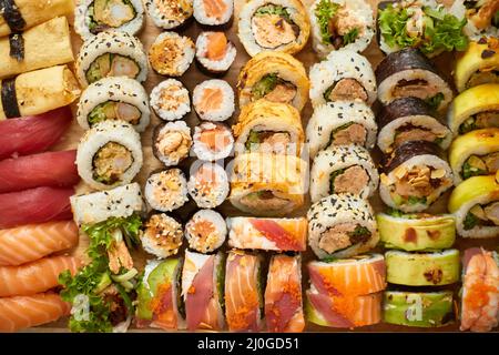 Vista dall'alto con set di diversi tipi di colori panini di sushi posti su tavola di legno Foto Stock