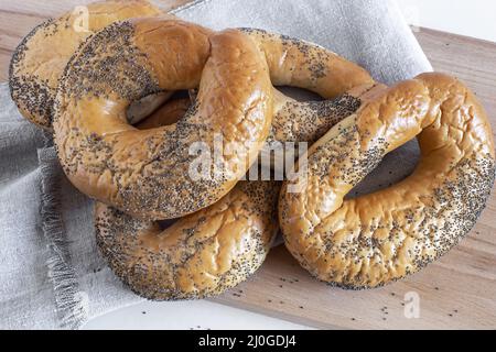 Bagel con semi di papavero su un tagliere Foto Stock