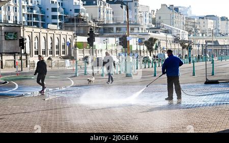 Brighton UK 19th marzo 2022 - i camminatori catturano un certo spruzzo da un lavoratore di mattina presto lungo il lungomare di Brighton su che cosa è previsto essere il giorno più caldo dell'anno finora con alcune parti della Gran Bretagna sono previsti per raggiungere l'alto centigrado degli anni dell'adolescenza : Credit Simon Dack / Alamy Live News Foto Stock