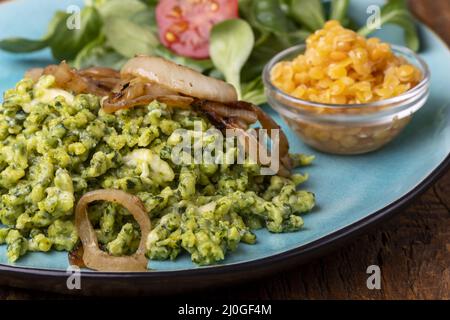 Spinaci bavaresi spaetzle su un piatto blu Foto Stock