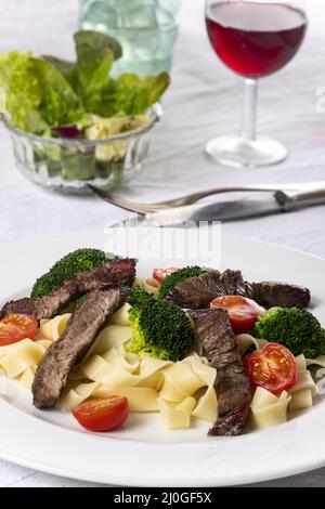 Tagliatelli con fette di bistecca sul piatto Foto Stock