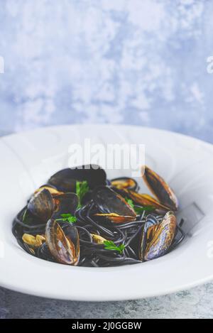 Spaghetti di pesce nero con cozze su fondo di pietra. Cibo mediterraneo delizioso Foto Stock