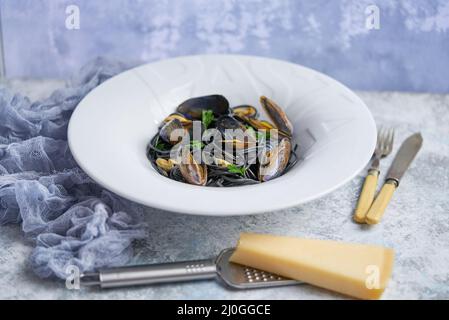 Spaghetti di pesce nero con cozze su fondo di pietra. Cibo mediterraneo delizioso Foto Stock
