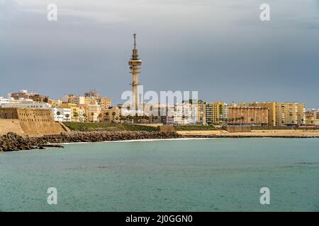 Die Küste mit dem Telekommunikations Turm la Torre Tavira II und dem Strand Playa de Santa María del Mar in Cádiz, Andalusia, Spanien | la costa w Foto Stock