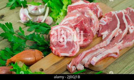 Fette fresche di montone e verdure assortite su scrivania in legno naturale Foto Stock