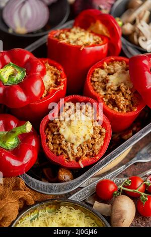 Peperoni di paprika ripieni di campana rossa in pentola da cucina con ferro da stiro vari ingredienti sul lato Foto Stock