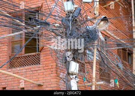 L'elettricità impigliata e i cavi di telecomunicazione sui poli di un edificio Foto Stock