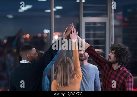 I giovani uomini d'affari multietnici che si divertono a celebrare il successo aziendale condiviso o la vittoria in carica. Sorridente multirazziale diversi dipendenti sentire Foto Stock