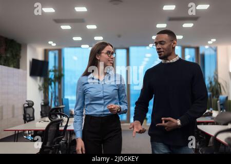 Due felici e diversi professionisti dirigenti business team persone donna e African American uomo a piedi in ufficio di coworking. Azienda multiculturale Foto Stock