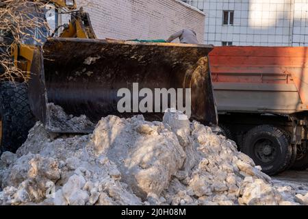 Il bulldozer rastrema pezzi di ghiaccio dopo una nevicata. Rimozione della neve da strade e cantieri. Trasporto municipale al lavoro Foto Stock