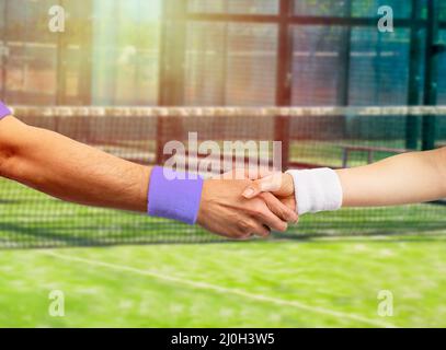 Scatto corto di due giovani giocatori di tennis che scuotono le mani insieme all'aperto sul campo Foto Stock