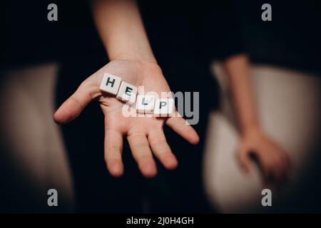 Ragazza che chiede aiuto. Ragazza allunga le mani con la parola aiuto nelle sue palme Foto Stock