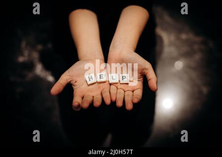 Ragazza che chiede aiuto. Ragazza allunga le mani con la parola aiuto nelle sue palme Foto Stock