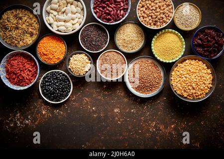 Varie superfoods in piccole ciotole scuro su sfondo arrugginito Foto Stock