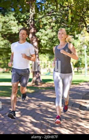 Calorie brucianti in coppia. Una coppia in abbigliamento sportivo che corre attraverso il parco. Foto Stock