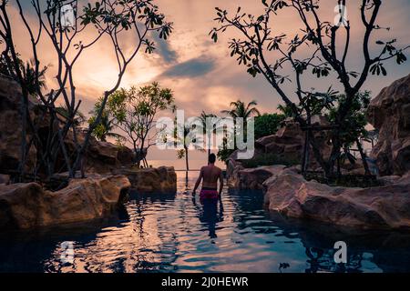 Piscina di lusso in un resort tropicale, vacanze rilassanti in Thailandia. , Giovane durante il tramonto da swimpool a Pattaya Foto Stock