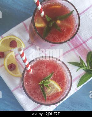 Succo di anguria in un bicchiere con limone e lamponi. Foto Stock