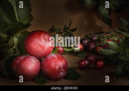 Frutta di susina matura e succosa su sfondo di legno scuro alla rinfusa Foto Stock