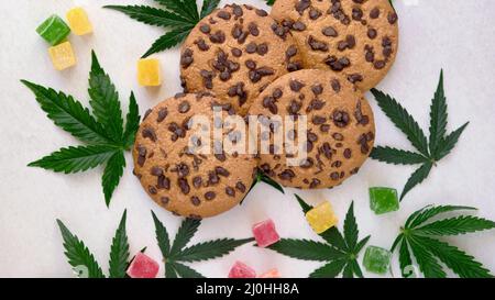 Biscotti americani con estratto di cannabis. Dolci con olio CBD. Foglie di marijuana su sfondo bianco. Vista dall'alto, piatto. Foto Stock