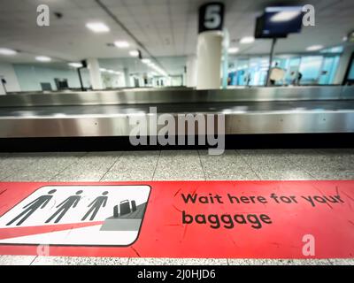 Una zona rossa sul pavimento che indica dove attendere il ritiro bagagli in aeroporto. Foto Stock