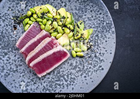 Stile moderno tradizionale giapponese gourmet pesce mare di tonno bistecca tataki con frutta avocado e fagioli di soia edamame servito come top v Foto Stock