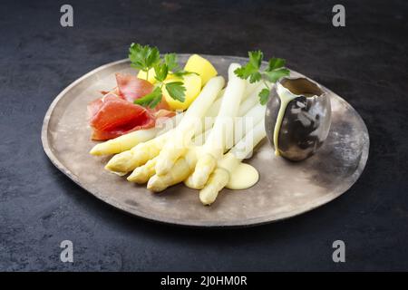 Tradizionale asparagi bianchi al vapore con prosciutto stagionato e patate bollite guarnite con salsa di hollandaise servito da vicino su un Foto Stock