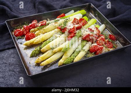 Tradizionale asparagi bianchi e verdi con pomodori e parmigiano servito da vicino su un vassoio di metallo rustico Foto Stock