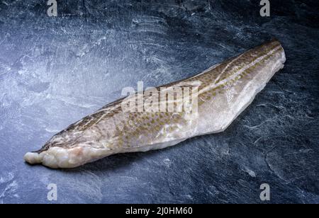 Raw Norwegian skrei cod fish filet with skin offered as close-up on black board with copy space Stock Photo