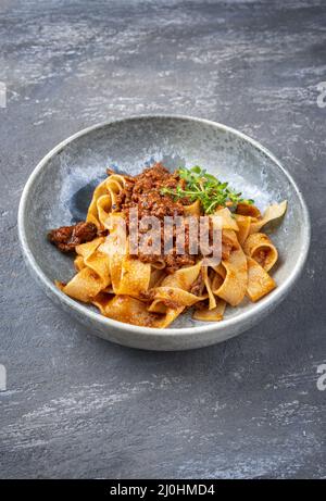 Salsa tradizionale italiana ragu alla bolognese in stile moderno con tagliatelle di pasta e parmigiano servito come primo piano Foto Stock