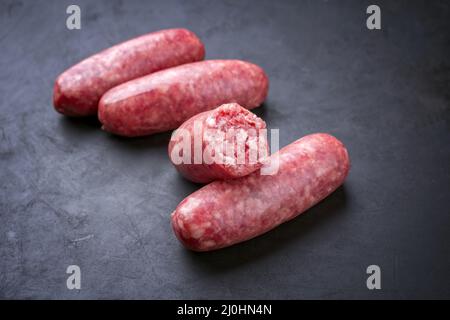 Tradizionale salsiccia cruda italiana affumicata di carne offerto da vicino su una tavola nera rustica Foto Stock