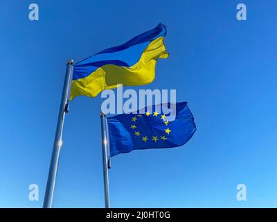 Bandiere ucraine e dell'Unione europea su pali di bandiera contro il cielo blu Foto Stock