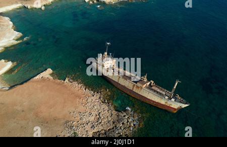 Vista aerea del drone di una nave abbandonata ormeggiata nella zona rocciosa costiera. Foto Stock