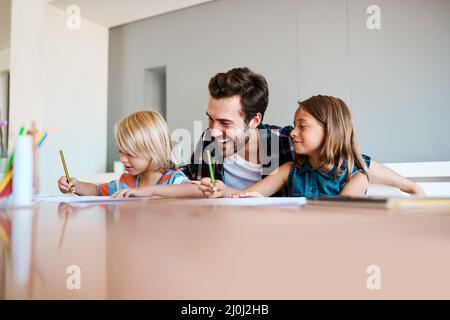 Amano appena quando il loro papà è intorno. Shot di un giovane padre che aiuta i suoi due figli piccoli con i loro compiti a casa. Foto Stock