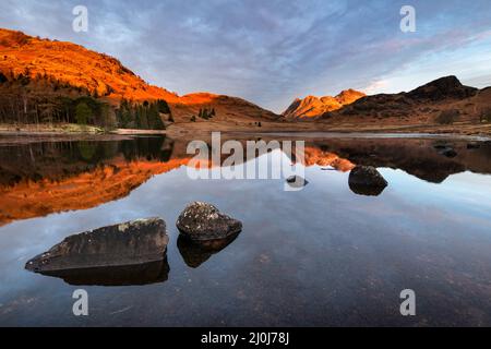 Riflessi nel lago all'alba in una mattina d'inverno a Blea Tarn nel Lake District. Paesaggi paesaggistici della Gran Bretagna rurale. Background della natura. Foto Stock