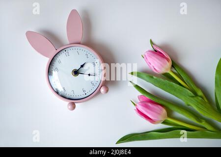 rosa sveglia orecchie di coniglio con tulipani. Carta di Pasqua. Fiori omaggio. Vista dall'alto dello spazio di copia a disposizione piatta Foto Stock