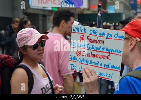 Un partecipante è visto tenere un banner anti-vaccinazione Covid-19 durante il World Freedom Rally a Times Square a New York City il 19 marzo 2022. Foto Stock